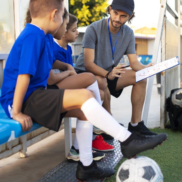 football-trainer-teaching-kids-full-shot